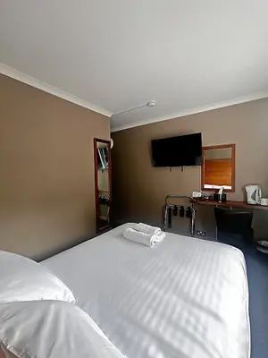 a bedroom with a bed and a desk and a television at Park Hotel in Falkirk