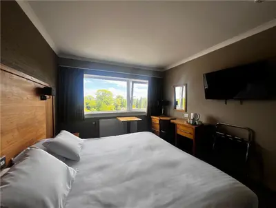 a bedroom with a large white bed and a window at Park Hotel in Falkirk
