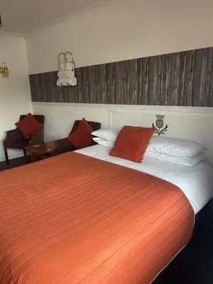 a bedroom with a large bed with an orange blanket at The Thistle in Stranraer