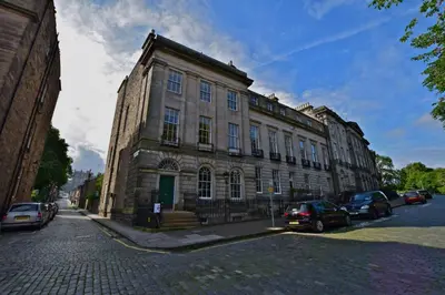 a large stone building with cars parked in front of it at JOIVY Spacious Apt in New Town Prime Location in Edinburgh