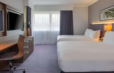 a hotel room with two beds and a desk and a tv at DoubleTree by Hilton Edinburgh Airport in Ingliston