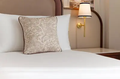 a white bed with a pillow and a lamp at The Caledonian Edinburgh, Curio Collection by Hilton in Edinburgh