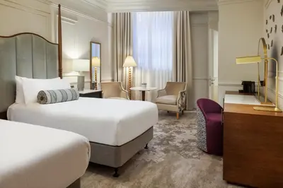 a hotel room with two beds and a desk at The Caledonian Edinburgh, Curio Collection by Hilton in Edinburgh