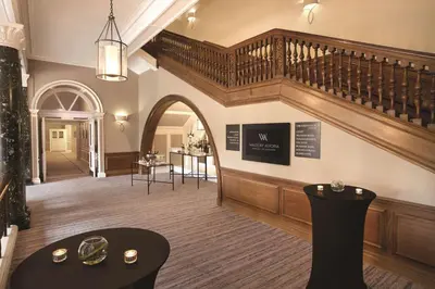a large lobby with a staircase and tables and chairs at The Caledonian Edinburgh, Curio Collection by Hilton in Edinburgh