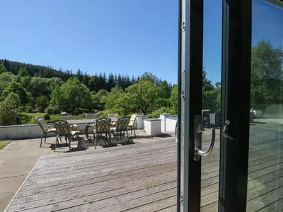 an open door with chairs and tables on a deck at Sobrachan in Braevallich