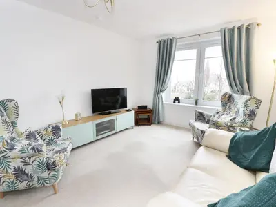 a living room with two chairs and a television at MACS Place in Largs