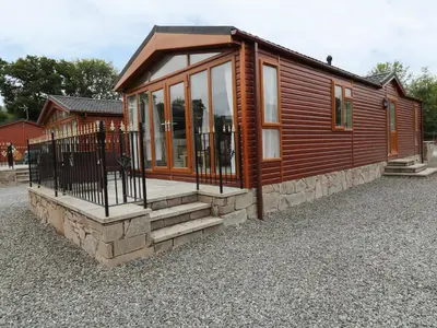 a small cabin with glass doors and a porch at 32 Cruachan Lodge in Auchterarder