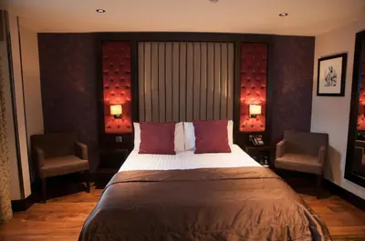 a bedroom with a large bed and two chairs at The Torrance Hotel in East Kilbride