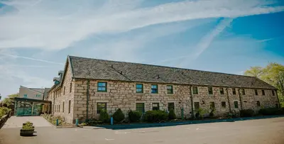 a large stone building with a blue sky in the background at The Torrance Hotel in East Kilbride