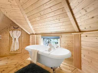 a bathroom with a white tub in a wooden ceiling at Aos Sí Lodges in Ballachulish