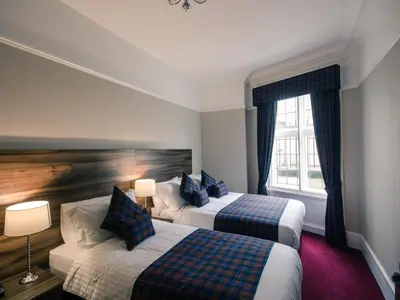 a hotel room with two beds and a window at Royal West End Hotel in Glasgow