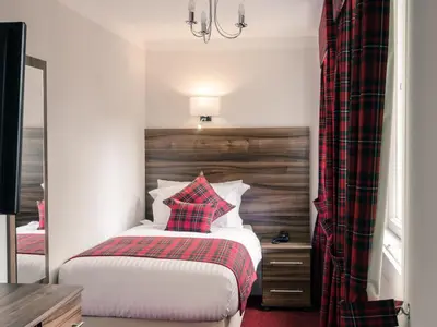 a bedroom with a bed with a red checked pillow at Royal West End Hotel in Glasgow
