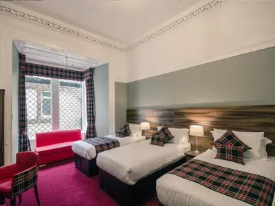 a hotel room with two beds and a red chair at Royal West End Hotel in Glasgow