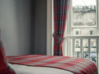 a bedroom with a bed and a window with curtains at Royal West End Hotel in Glasgow