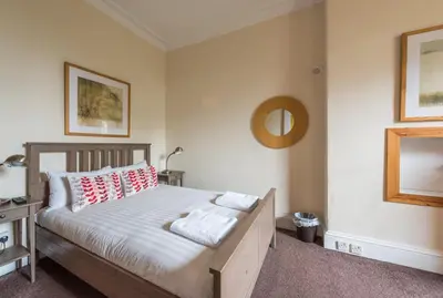a bedroom with a bed with red and white pillows at 3 bed overlooking meadows park in Edinburgh