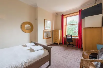 a bedroom with a bed and a desk and a window at 3 bed overlooking meadows park in Edinburgh