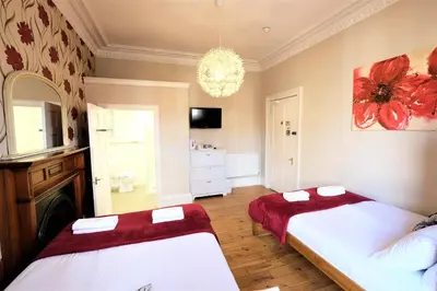 a bedroom with two beds and a chandelier at Balmore Guest House in Edinburgh