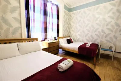 a hotel room with two beds and a window at Balmore Guest House in Edinburgh