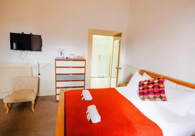 a bedroom with a bed with a red blanket and a chair at Balmore Guest House in Edinburgh