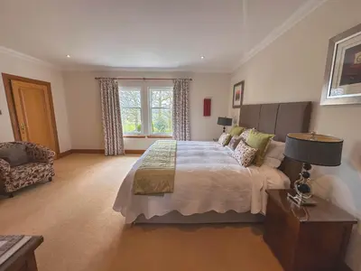 a bedroom with a bed and a chair and a window at Arden Country House in Linlithgow