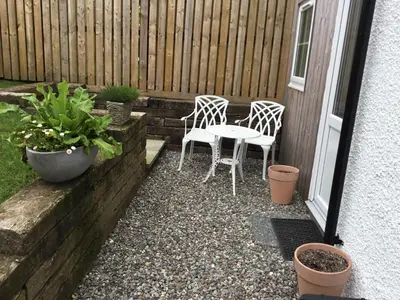 a patio with two chairs and a table and some plants at Burn View in Stronachlachar