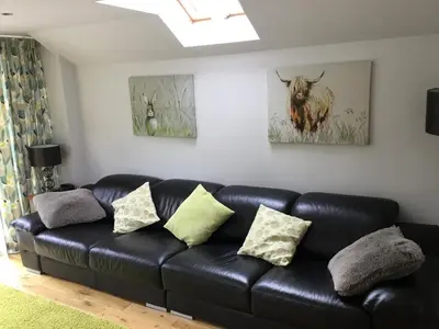 a black leather couch with pillows in a living room at Burn View in Stronachlachar