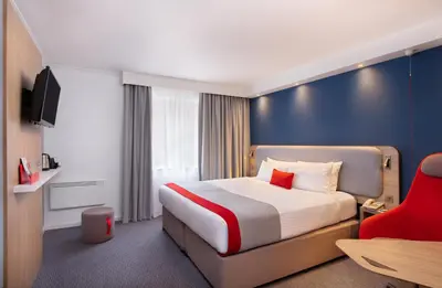 a hotel room with a bed and a red chair at Holiday Inn Express Strathclyde Park M74, Jct 5 by IHG in Motherwell