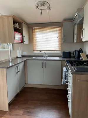 a kitchen with white cabinets and a sink and a stove at Swift bordeaux 24 in Dunoon