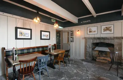 a restaurant with tables and chairs and a fireplace at Ardencaple Hotel by Greene King Inns in Helensburgh