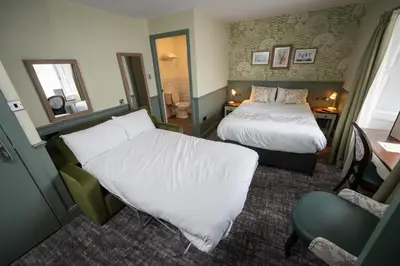 a hotel room with a bed and a chair at Ardencaple Hotel by Greene King Inns in Helensburgh