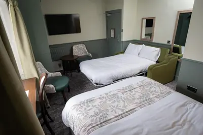 a hotel room with two beds and a table and chairs at Ardencaple Hotel by Greene King Inns in Helensburgh