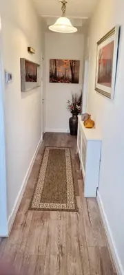 a hallway with white walls and wooden floors and a rug at Churchview in Townhill