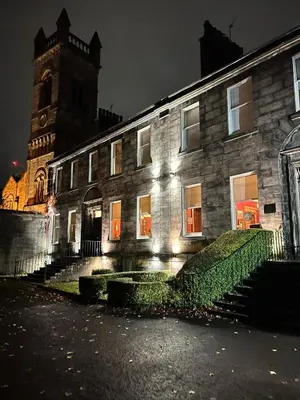 a stone building with a clock tower at night at Ashtree House Hotel, Glasgow Airport & Paisley in Paisley