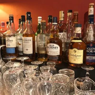 a bunch of alcohol bottles and glasses on a table at Ashtree House Hotel, Glasgow Airport & Paisley in Paisley