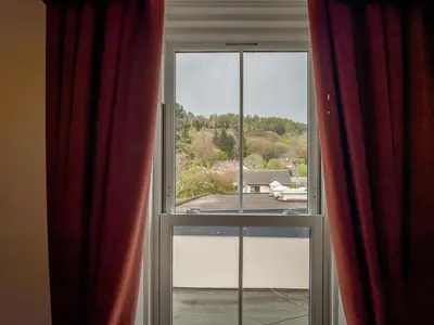 an open window with red curtains and a view at The Crags Hotel in Callander