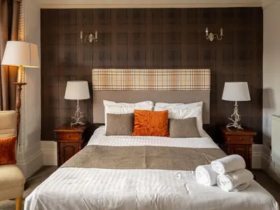 a bedroom with a large bed with pillows and two lamps at The Crags Hotel in Callander