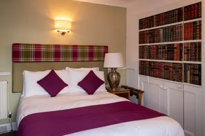 a bedroom with a bed with purple and white sheets at The Crags Hotel in Callander