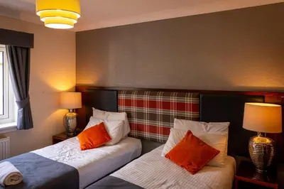 two beds in a room with two lamps at The Crags Hotel in Callander