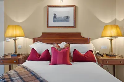 a bedroom with a bed with red pillows and two lamps at The Ugadale Hotel in Campbeltown