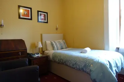 a bedroom with a bed and a dresser and a window at Ashgrove House in Edinburgh