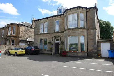 an old brick building with cars parked in a parking lot at Ashgrove House in Edinburgh