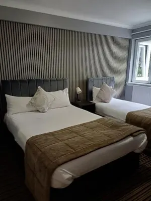 a hotel room with two beds and a window at Kings Park Hotel in Glasgow