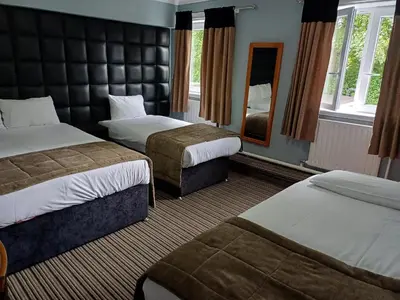 a hotel room with two beds and a mirror at Kings Park Hotel in Glasgow