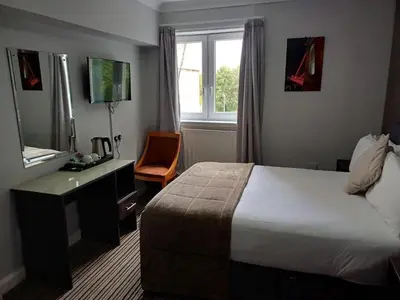a hotel room with a bed and a desk and a window at Kings Park Hotel in Glasgow