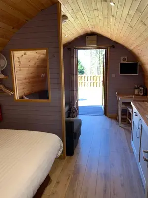 a bedroom with a bed and a kitchen with a table at Kersebrock Kabins in Falkirk