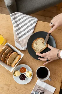 a woman is cutting a piece of bread on a table at Castle Park Guest House in Edinburgh