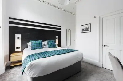 a bedroom with a large bed with blue and green pillows at Castle Park Guest House in Edinburgh