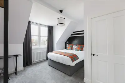 a white bedroom with a bed and a window at Castle Park Guest House in Edinburgh