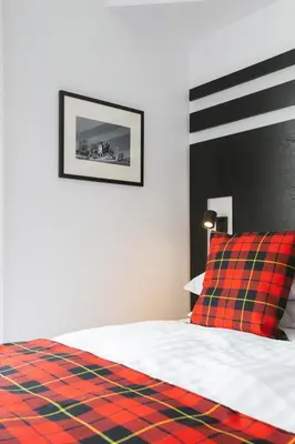 a bedroom with a bed with a red and green plaid pillow at Castle Park Guest House in Edinburgh