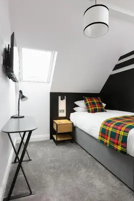 a bedroom with a bed and a tv and a table at Castle Park Guest House in Edinburgh